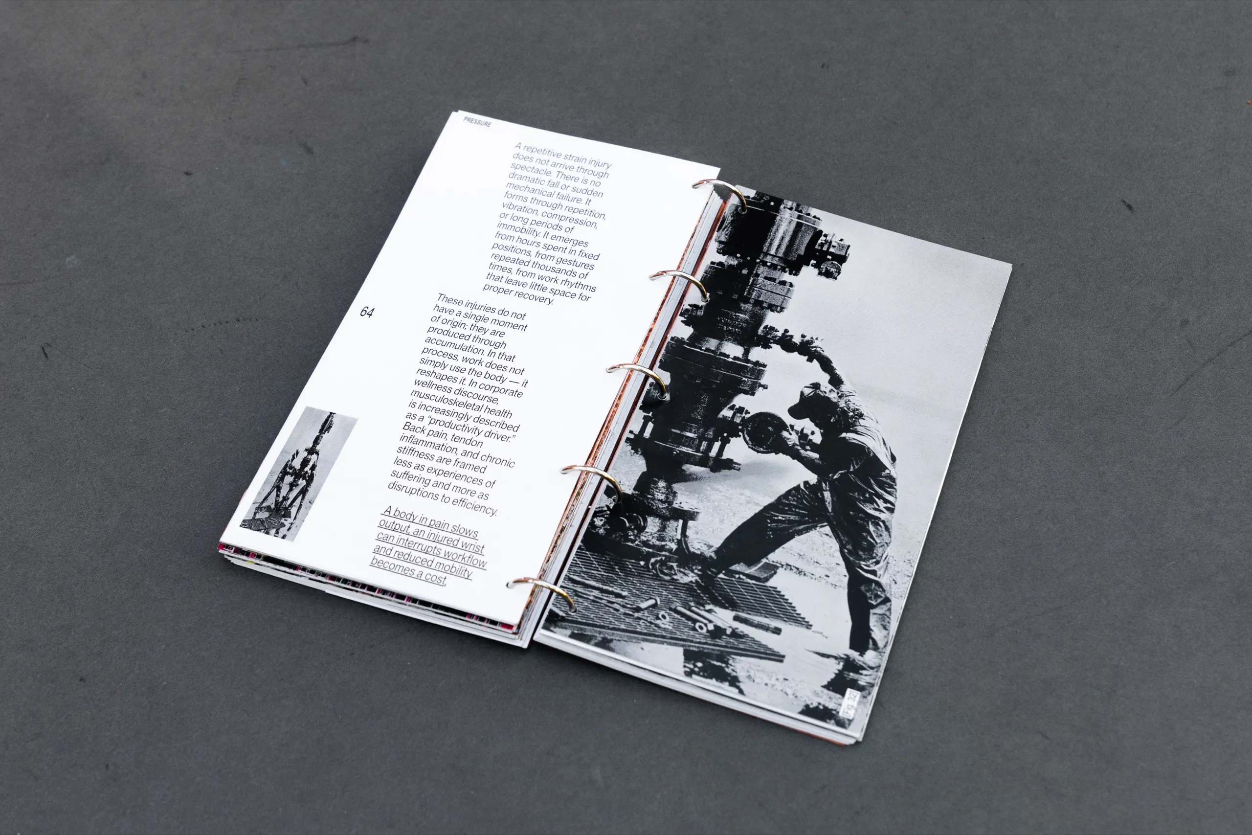 Hostilia open on a page with a black and white photograph of a worker