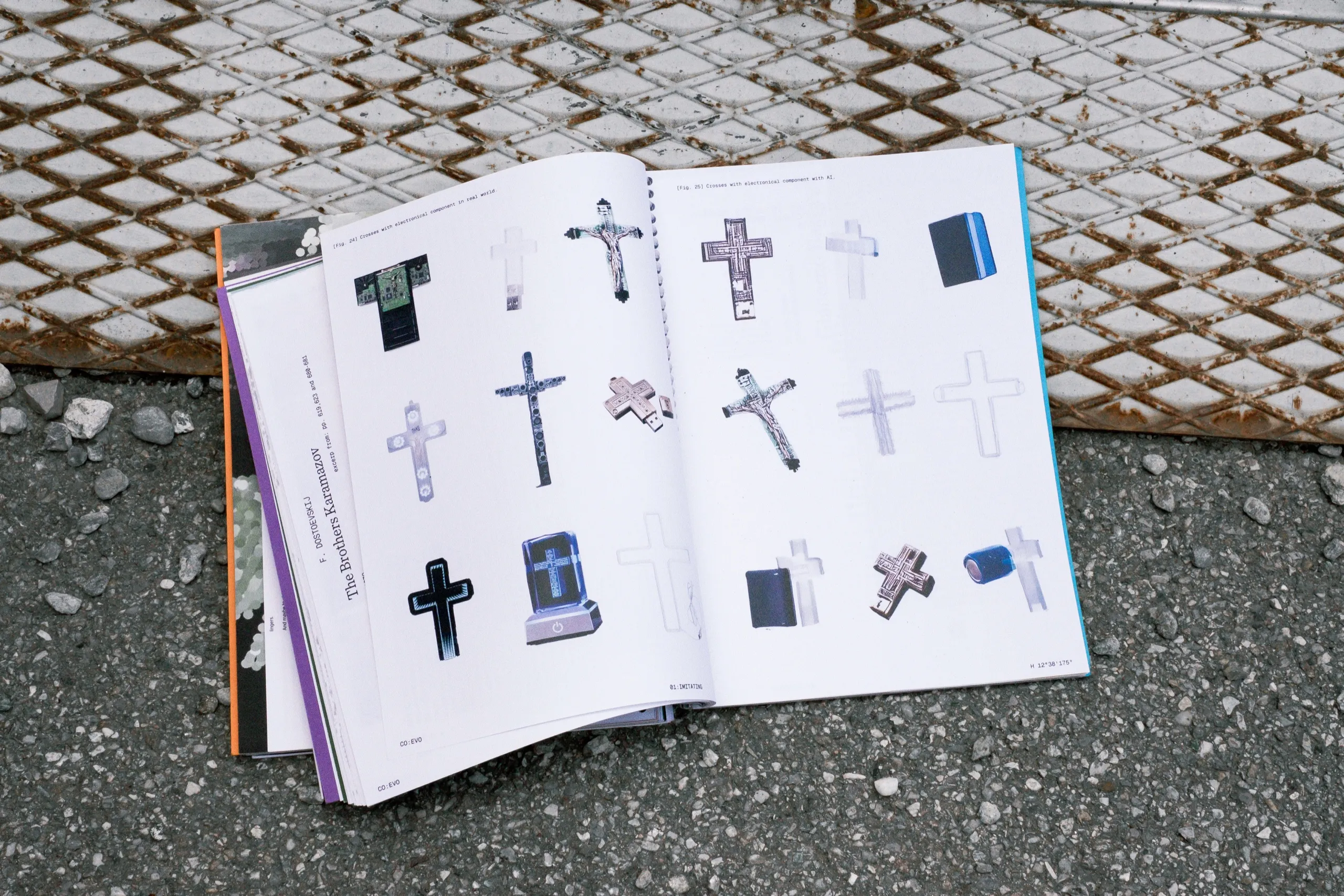 co:evo open on the ground on a spread of crosses and crucifixes, next to a rusty metal grate